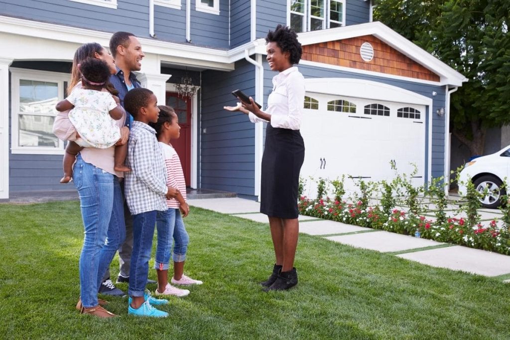 Real estate agent outside home discussing with family if they shouldStage Home or Sell Vacant